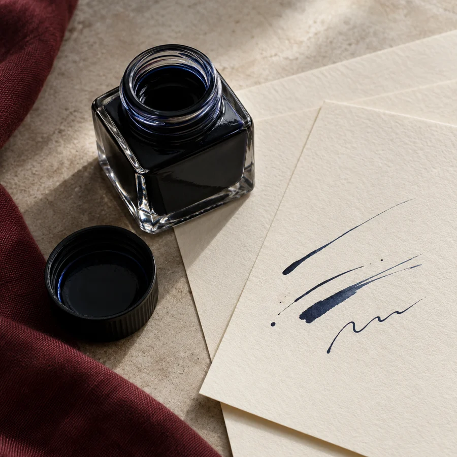 Blue-black fountain pen ink and writing paper, an editorial still life